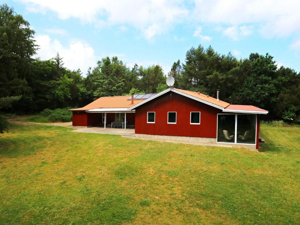 ein rotes Haus auf einem Feld neben einem Wald in der Unterkunft Holiday home Fårevejle XXI in Fårevejle