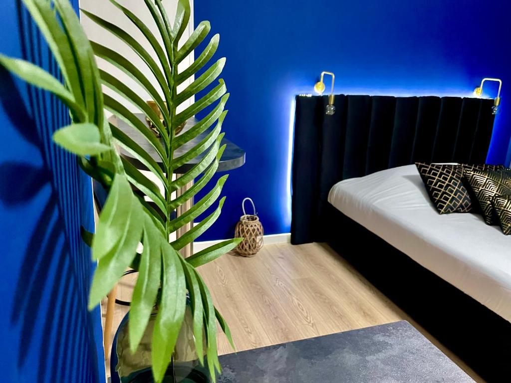 Habitación azul con sofá y planta en L'appart Botanic Metz, en Metz