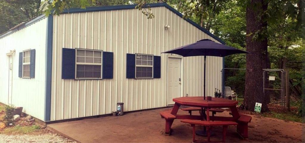 einem Picknicktisch mit einem Regenschirm vor einem Gebäude in der Unterkunft Cute Shouse Unit 2 in Ozark