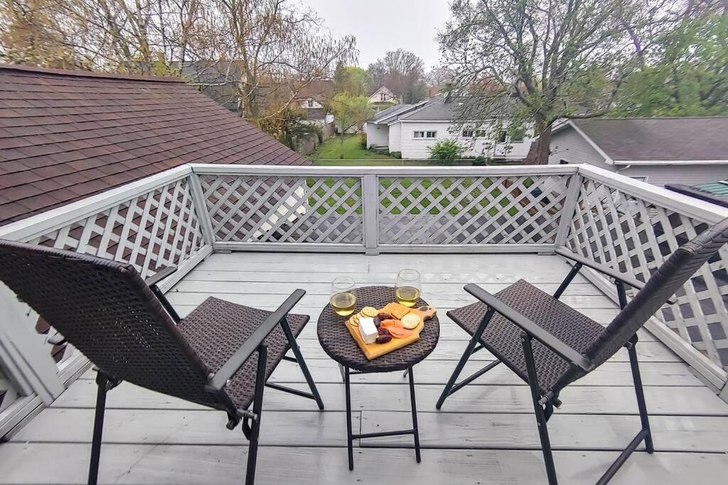 un balcón con 2 sillas y una mesa con un bol de fruta en Historic w/deck, king bed & air by Lake Michigan en Manistee