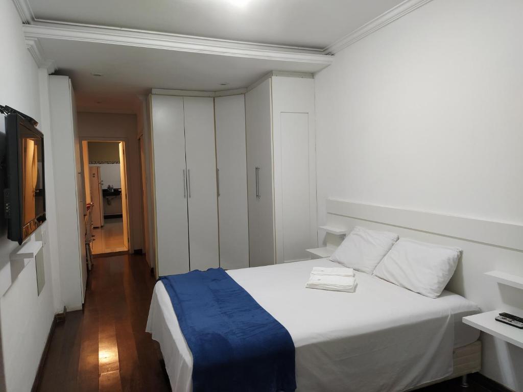 a bedroom with a white bed with a blue blanket at Estadia das Gerais - Casa de hóspedes adorável com Jacuzzi in Ouro Preto
