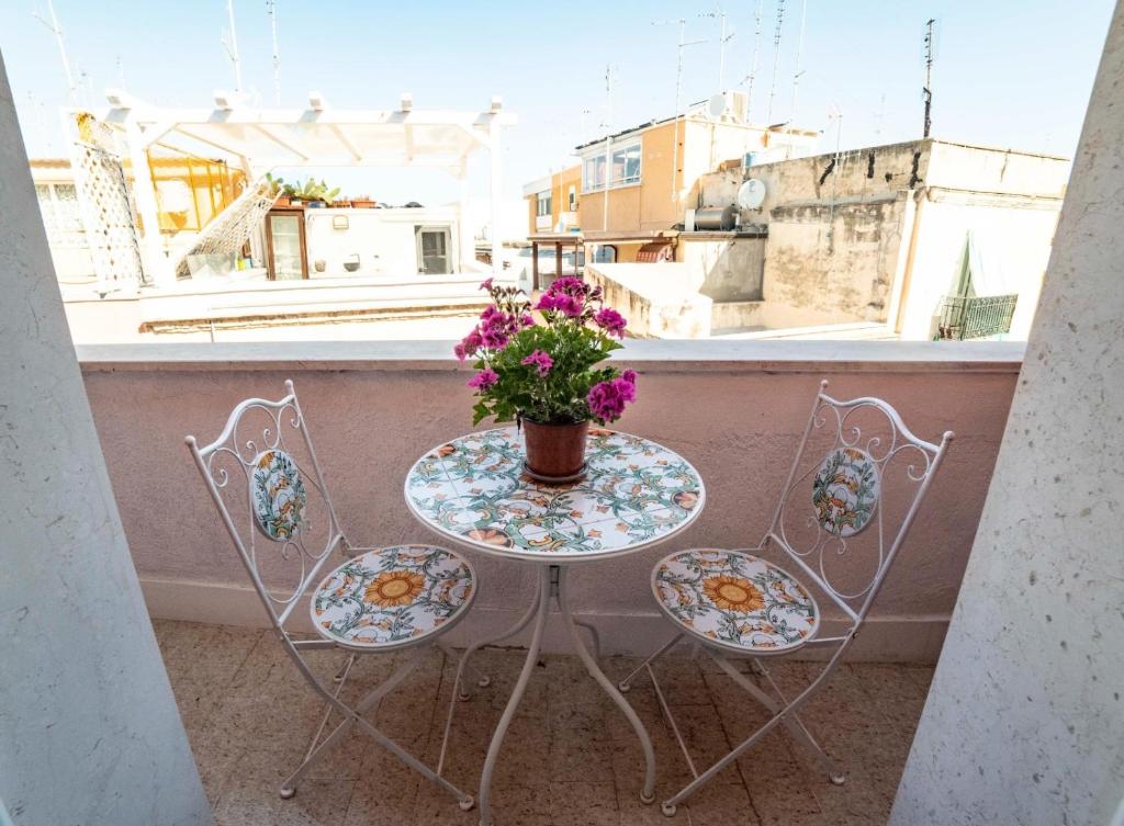 una mesa con un jarrón de flores en el balcón en Porto Antico en Bari