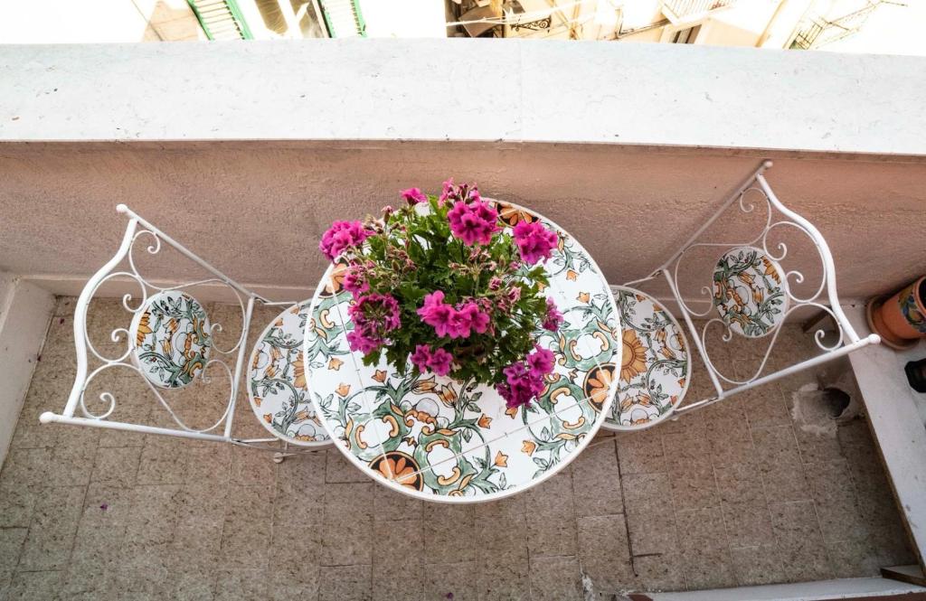 un tavolo con un vaso di fiori in cima a un balcone di Porto Antico a Bari