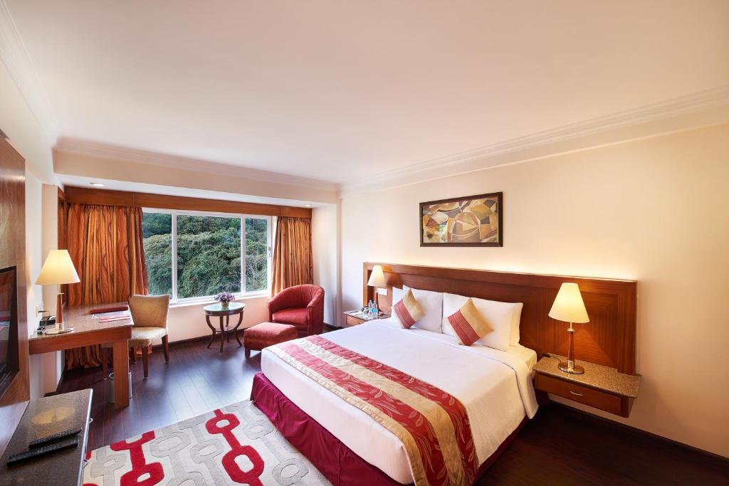 a hotel room with a large bed and a desk at Accord Highland Hotel Ooty in Ooty