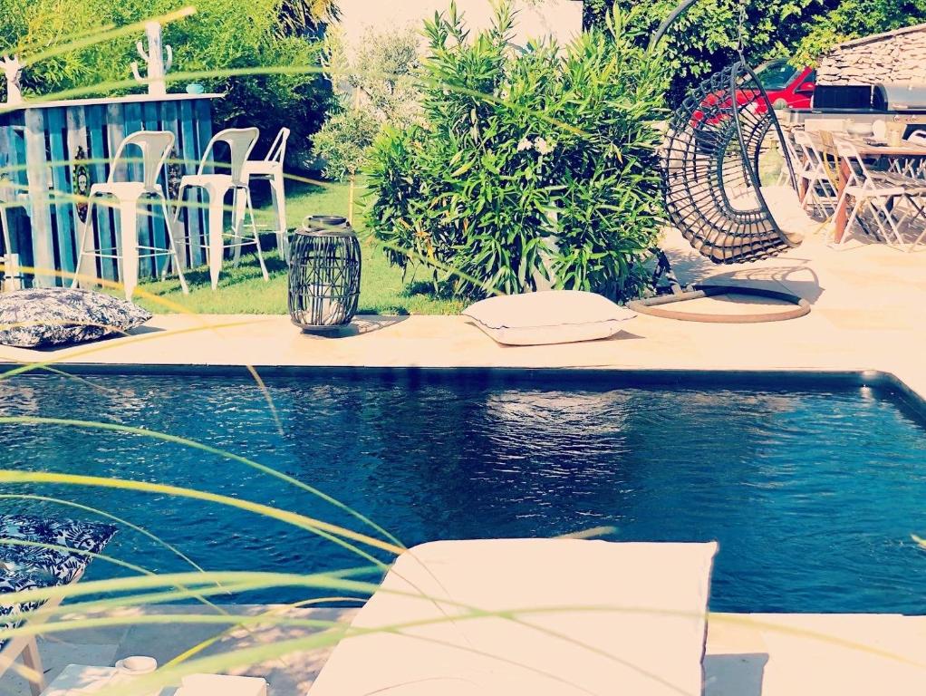 una piscina en un patio con sillas y mesa en Chambres D'hôtes Les Garçons, en Sarrians