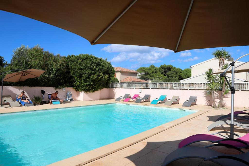 a swimming pool with chairs and an umbrella at U Libecciu in Macinaggio