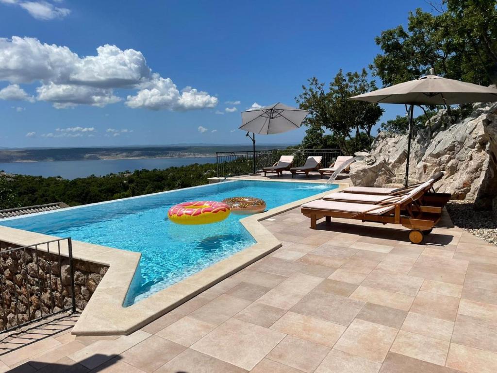 a swimming pool with an umbrella and two lounge chairs and an umbrella at Lovely Holiday Home in Starigrad with Private Swimming Pool in Starigrad-Paklenica