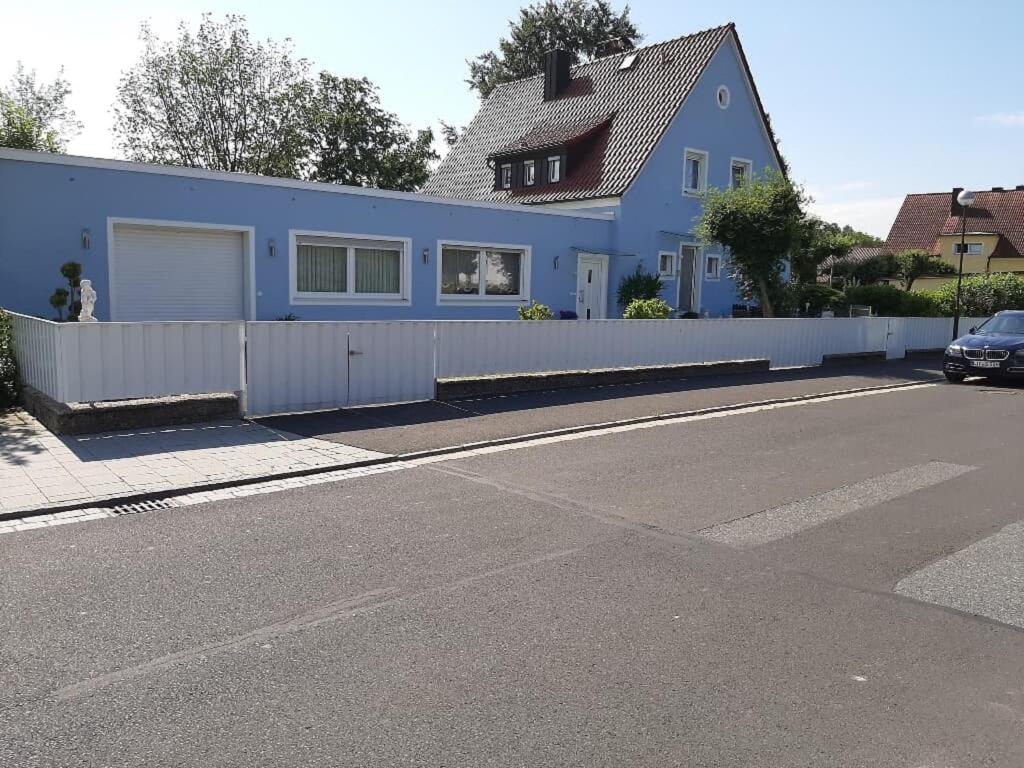 a blue house with a white fence next to a street at Ferienwohnung Inge in Waldsassen