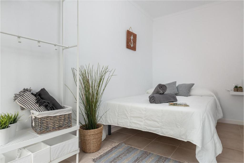 a white bedroom with a bed with plants on it at Sa Marineta in Porto Cristo