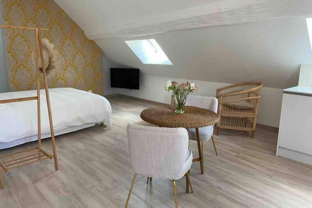 Un dormitorio con una cama y una mesa con flores. en Au coin des Hospices en Beaune