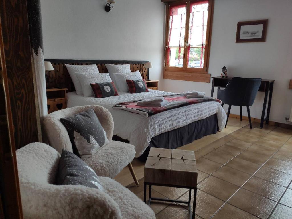 ein Schlafzimmer mit einem Bett, einem Stuhl und einem Sofa in der Unterkunft La Source Du Pré Masset in Métabief