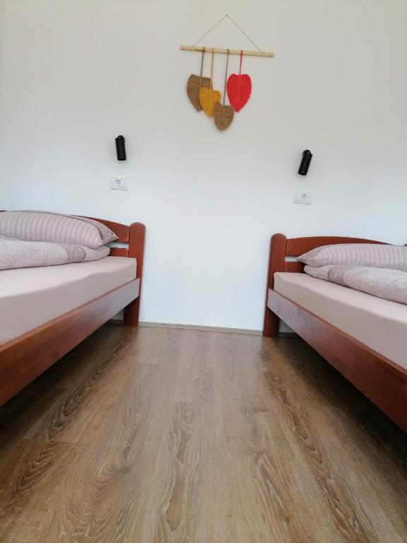 two beds in a room with a wooden floor at Nikolića kuća in Mitrovac