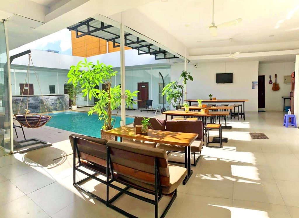 a room with tables and chairs and a swimming pool at Onederz Sihanoukville in Sihanoukville