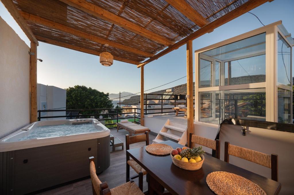 een balkon met een hot tub en een tafel en stoelen bij AKTI Homes Matala in Matala