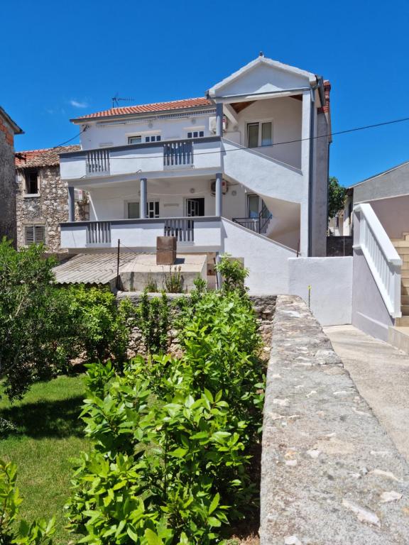 a large white house with a staircase in front of it at Apartmani Bada in Pakoštane