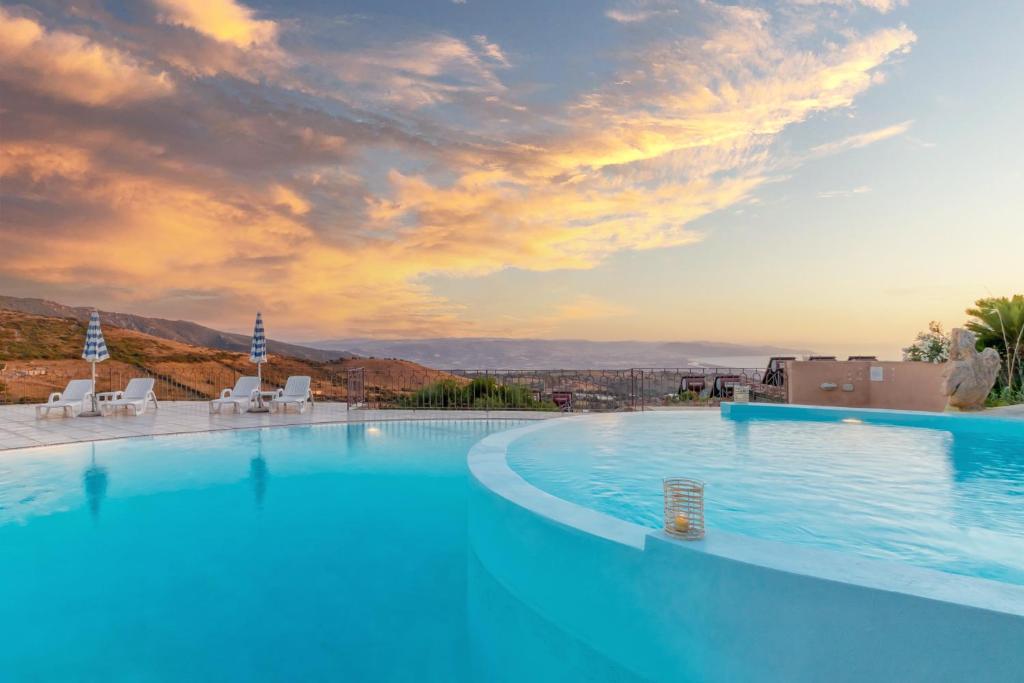 a large swimming pool with chairs and a sunset at Residence Pala Stiddata with panoramic swimming pool in Trinità d'Agultu e Vignola