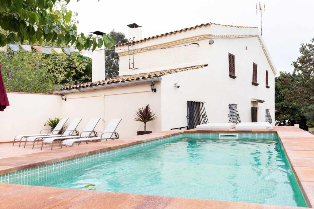 a swimming pool in front of a house at Masía Can Tramontana in Tiana