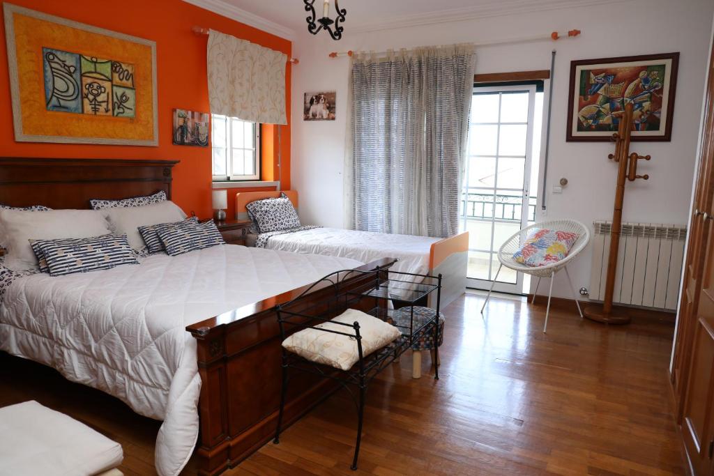ein Schlafzimmer mit 2 Betten und einer orangefarbenen Wand in der Unterkunft Casa da Avó Bela in Buarcos e São Julião