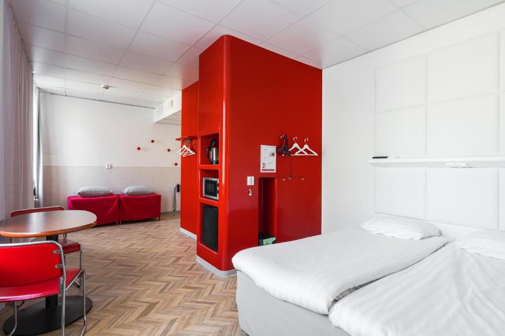 Cette chambre comprend un lit, une table et un mur rouge. dans l'établissement Omena Hotel Tampere, à Tampere