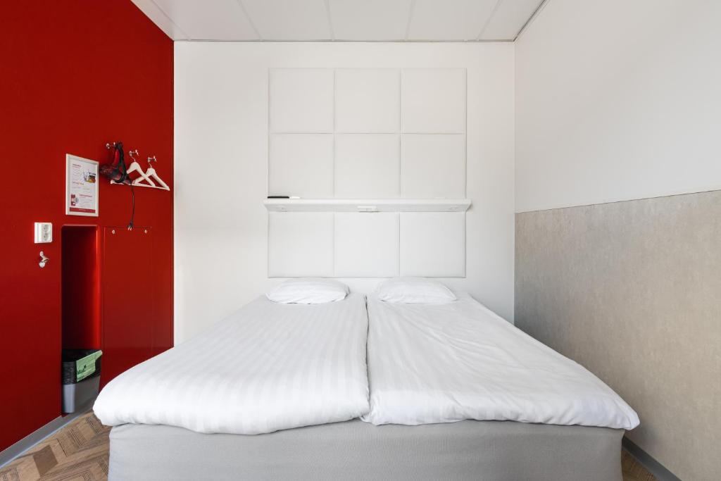 Cama blanca en habitación con pared roja en Omena Hotel Tampere en Tampere