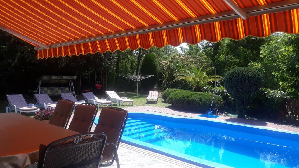 un patio con mesa y sillas y una piscina en Király Nyaraló, en Fonyód