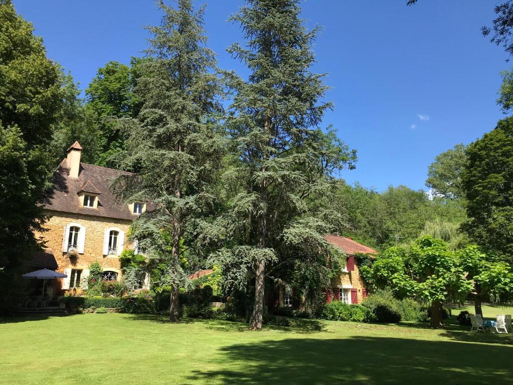 a house with two large trees in a yard at Bed & Breakfast Le Moulin Neuf in Saint-Alvère