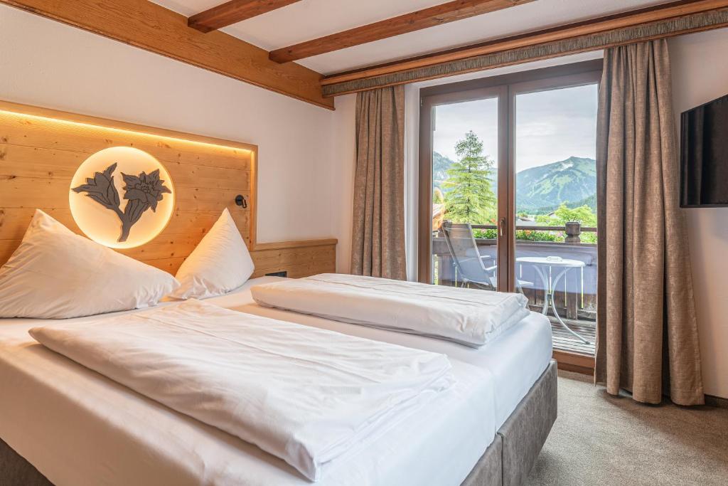 Hotel Tyrol am Haldensee في هالدينسي: غرفة نوم بسرير ونافذة كبيرة