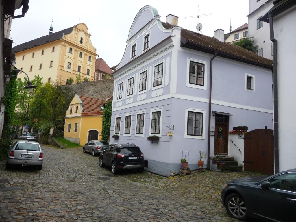 a white house with cars parked in a street at Penzion Kozák in Český Krumlov