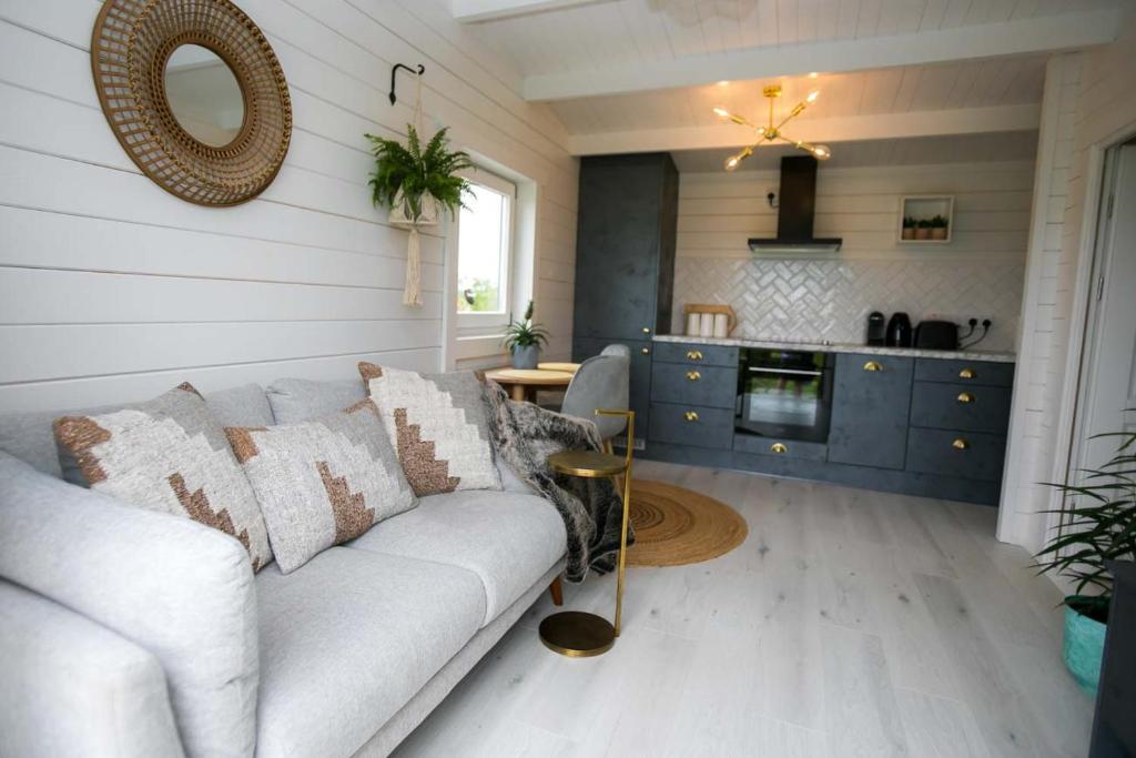 a living room with a couch and a kitchen at The Paddocks Cabin - Stylish, Cozy & Private in Killarney