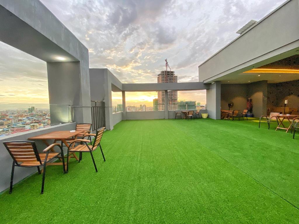 a balcony with green grass and tables and chairs at Yunfan Hotel in Phnom Penh