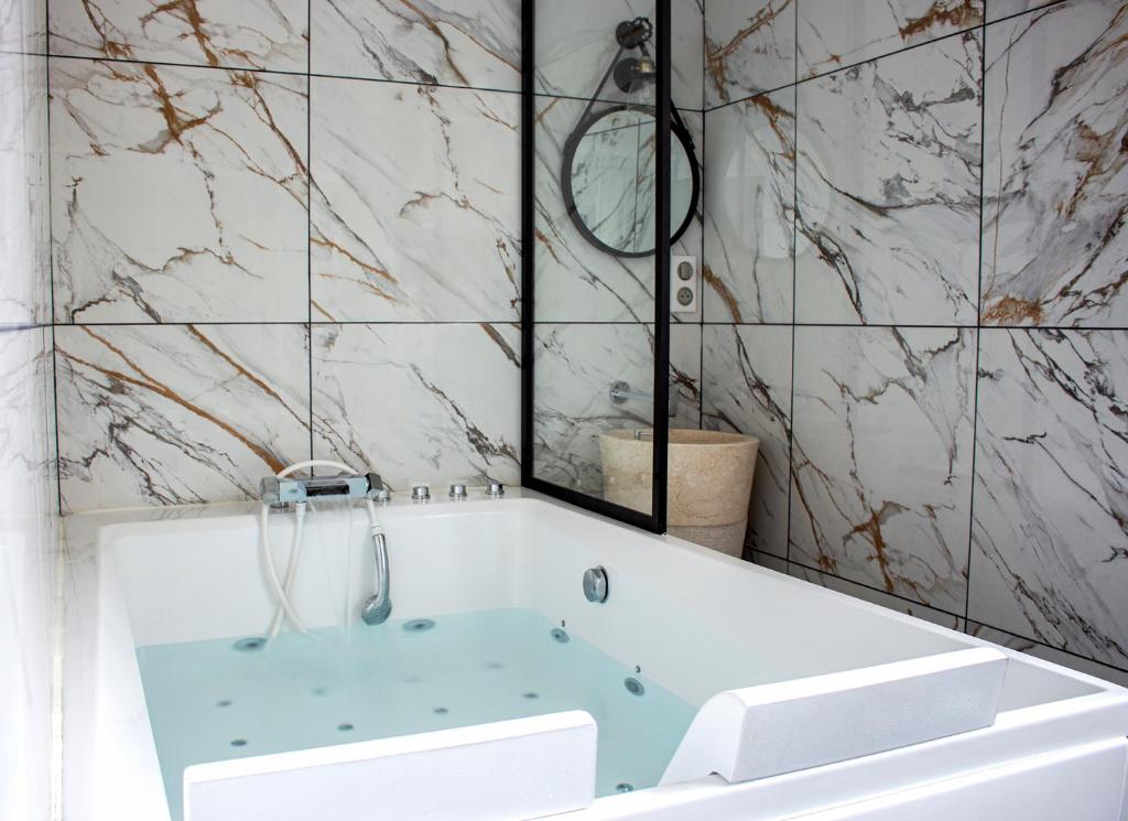 uma casa de banho com uma banheira e um espelho. em L'étoile et le Merveilleux 2 appartements SPA em Dijon