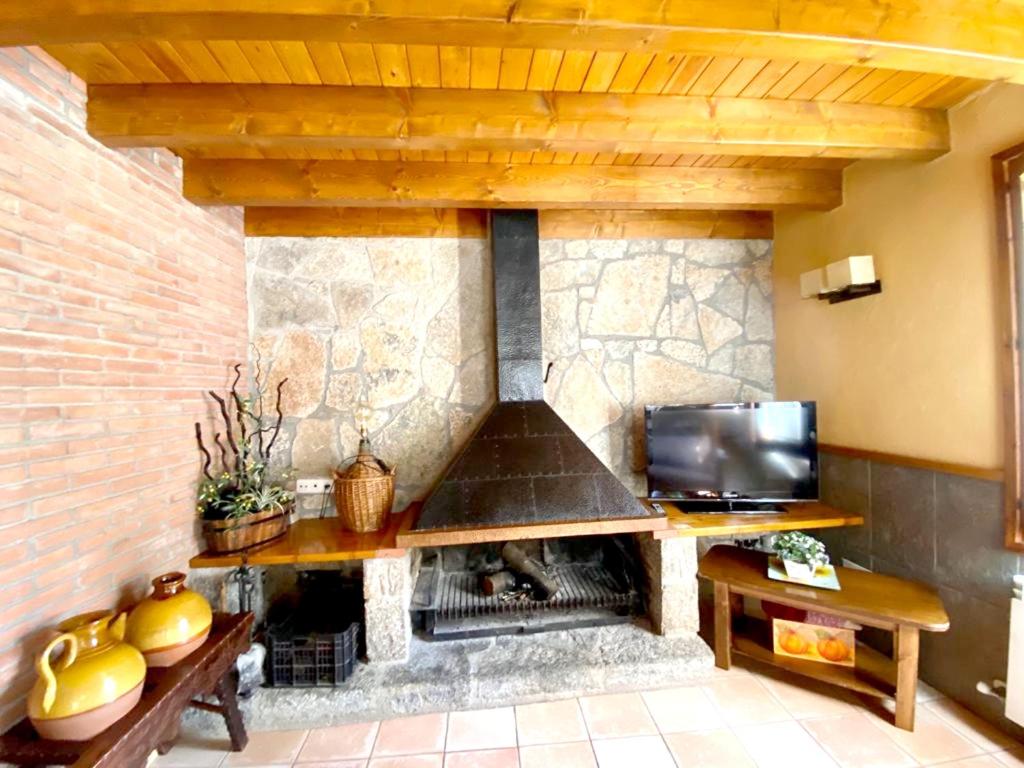 ein Steinkamin in einem Wohnzimmer mit Fernseher in der Unterkunft Spacious House in Ogassa with Terrace and BBQ in Ogassa