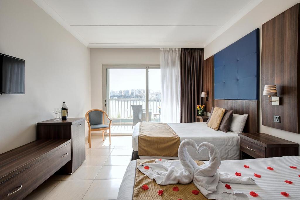 a hotel room with two beds with a swan decoration at Cavalieri Art Hotel in St. Julianʼs