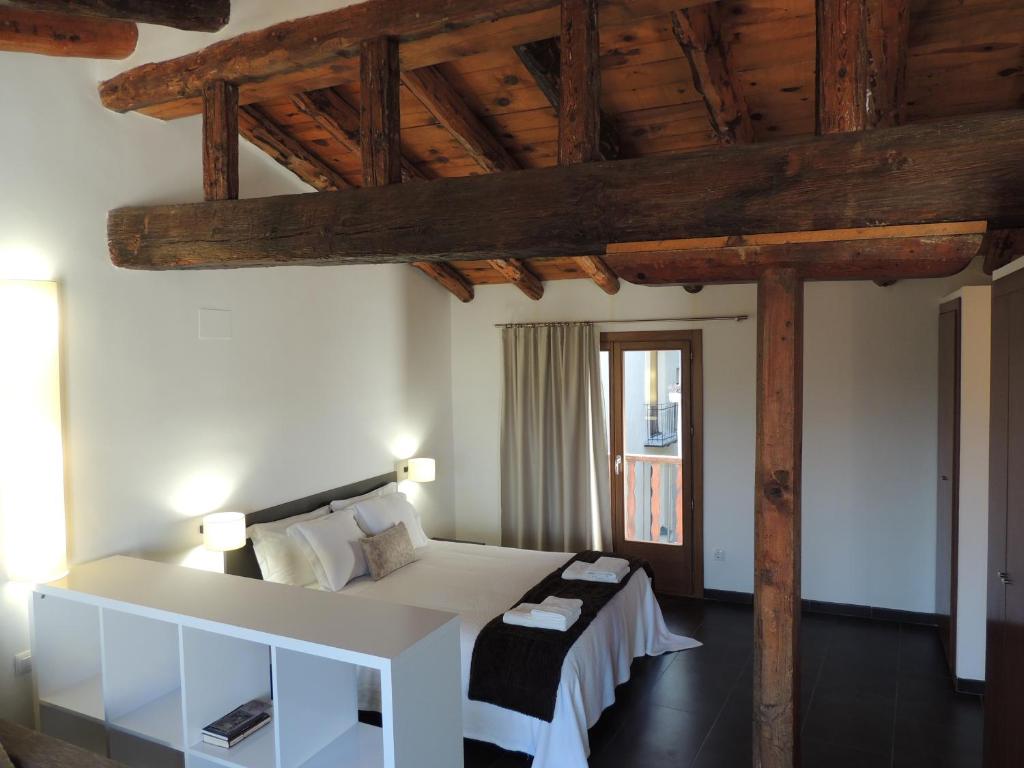 um quarto com uma cama branca e um tecto de madeira em Casa Rural Vistes de Morella em Morella