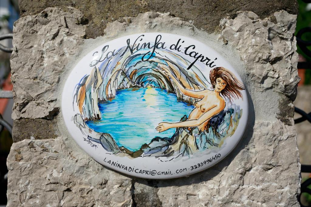 a sign on a wall with a mermaid painted on it at La Ninfa Di Capri in Anacapri