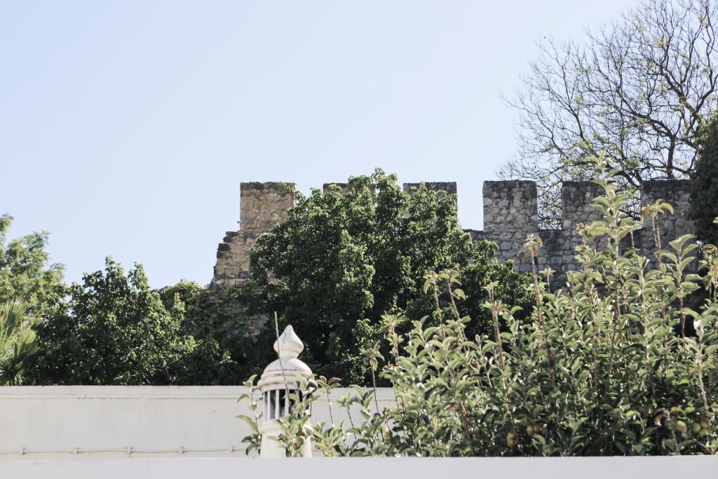 un castillo en el fondo con árboles y una valla blanca en A Muralha en Tavira