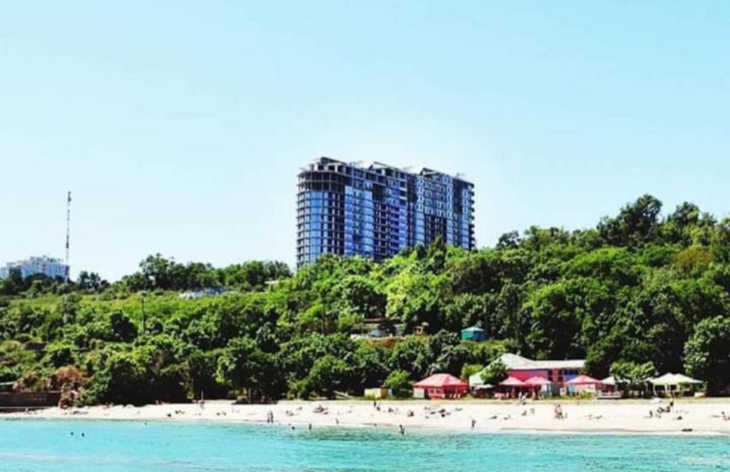 un groupe de personnes sur une plage avec un grand bâtiment dans l'établissement Apart hotel Greenwood near Sea, à Odessa