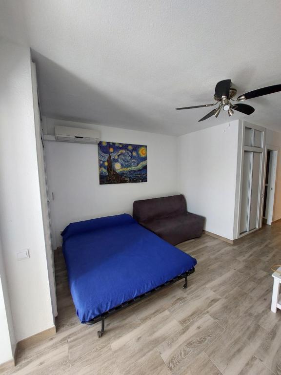 a bedroom with a bed and a couch and a ceiling fan at Edificio Agata in Benalmádena