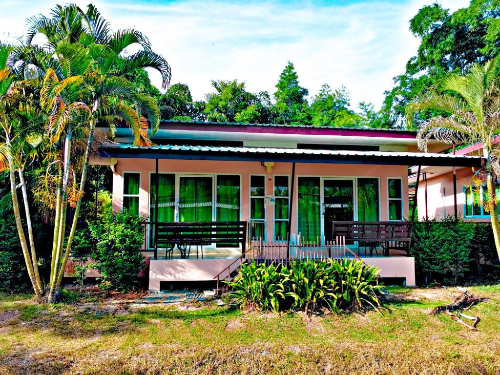 a house with a porch and palm trees at ภูร์ชรินท์ รีสอร์ท in Ban Than Phra