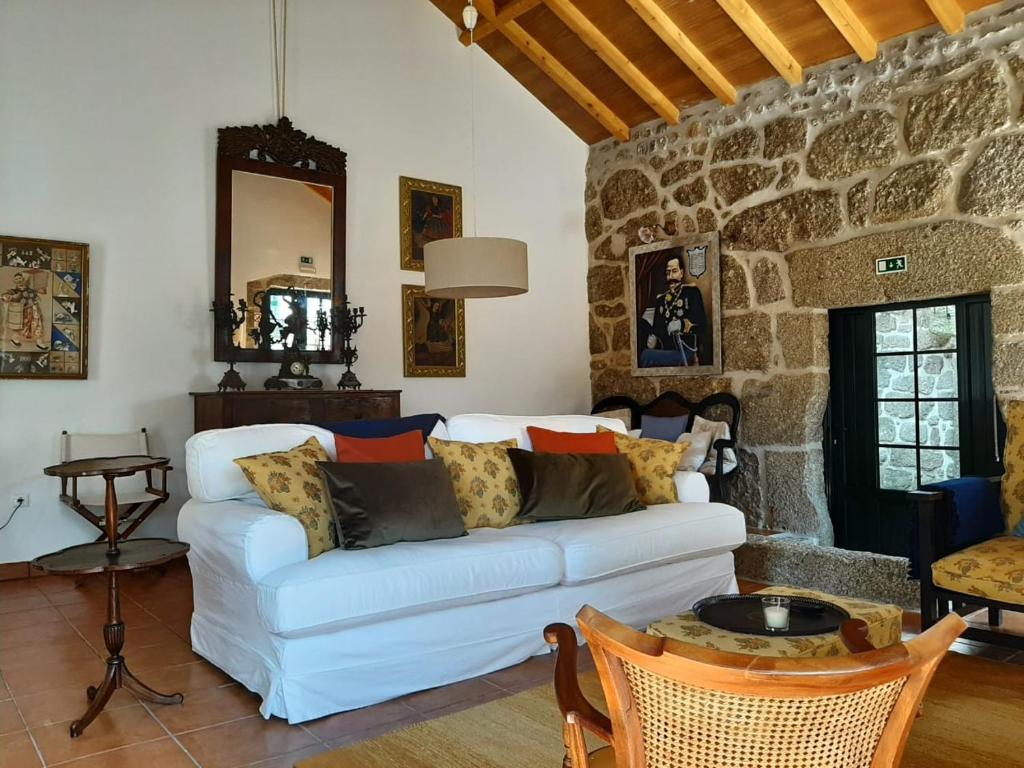 a living room with a white couch and a stone wall at Beautiful house and garden at Serra da Estrela, perfect for groups and families in Gouveia