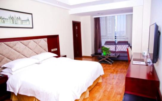 sypialnia z dużym białym łóżkiem i biurkiem w obiekcie GreenTree Inn SiChuan Chengdu Airport Road Zhujiang Road Express Hotel w mieście Chengdu