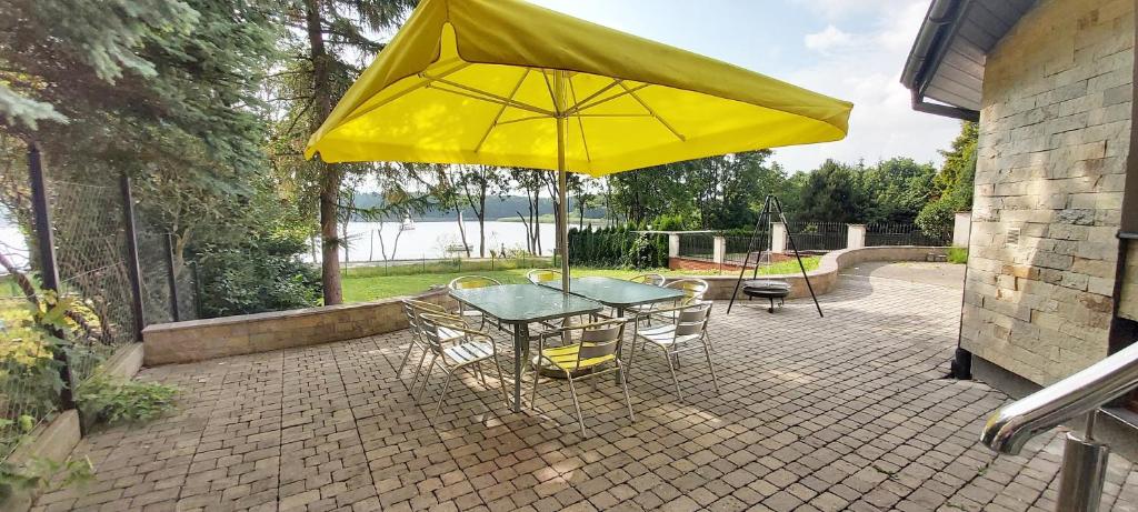 - une table et des chaises avec un parasol jaune sur la terrasse dans l'établissement Dom przy lini brzegowej Jezioraka, à Iława