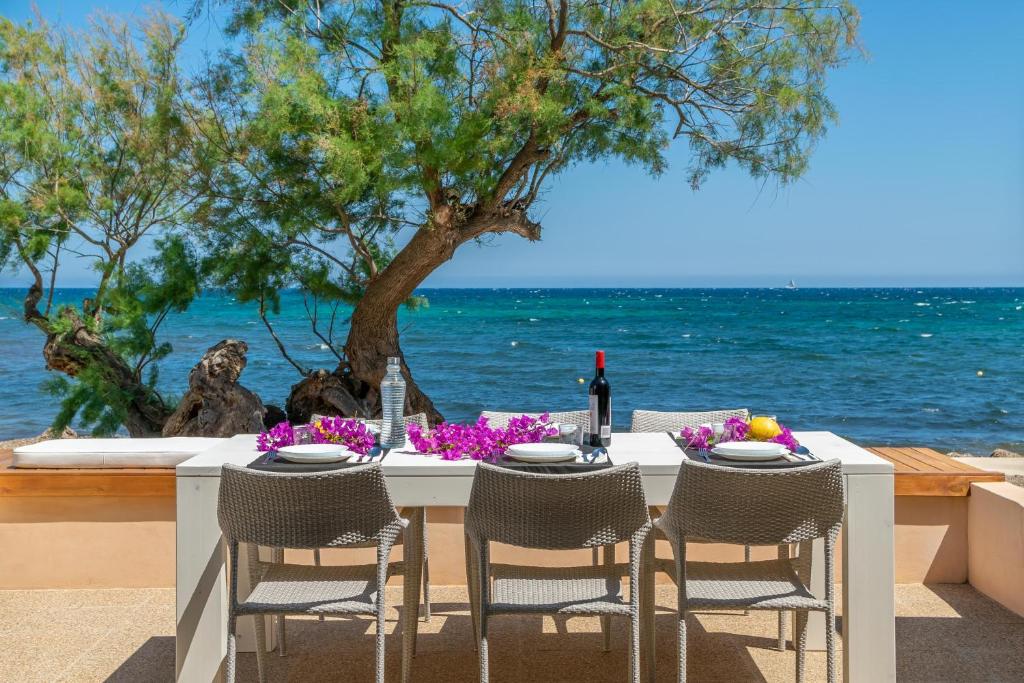 stół z krzesłami i stół z widokiem na ocean w obiekcie Cas Ferrerico w mieście Costa des Pins