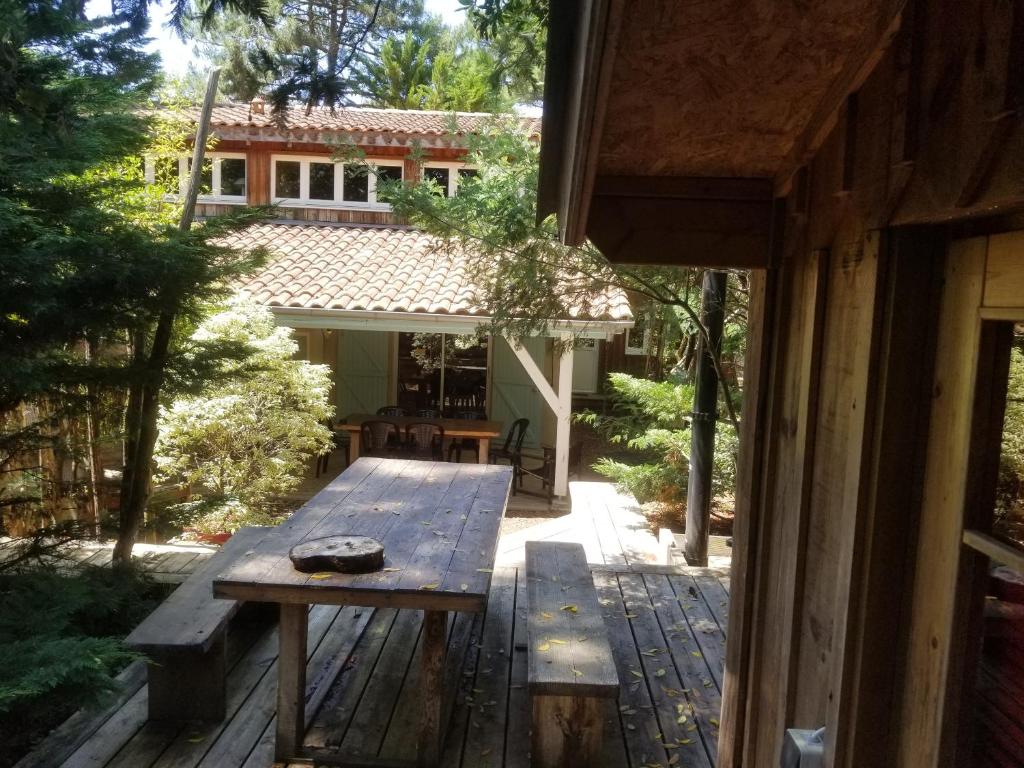 une table en bois assise sur une terrasse devant une maison dans l'établissement les cabanes, à Lège-Cap-Ferret