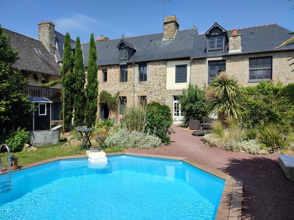 a swimming pool in front of a large house at Gites Le 1900 in Val Couesnon