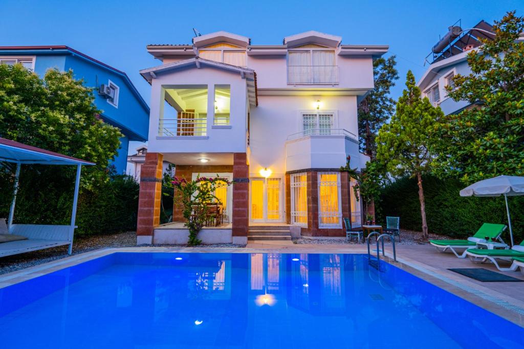 una casa con piscina frente a una casa en Infinity Beyaz Villa, en Fethiye