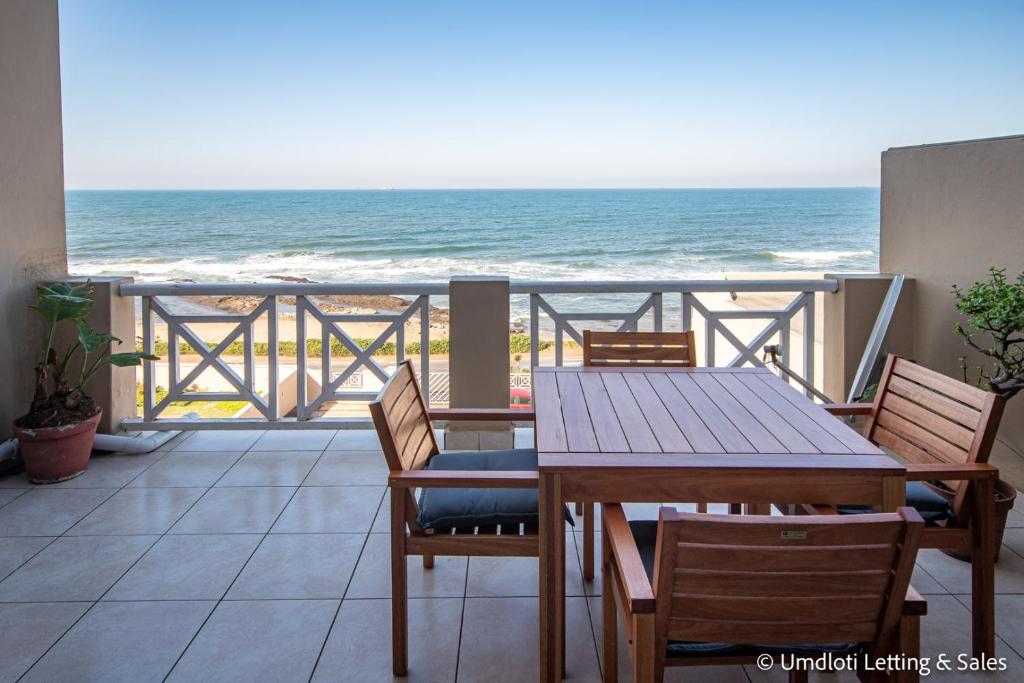 a balcony with a table and chairs and the ocean at Waterfront 22 in Umdloti