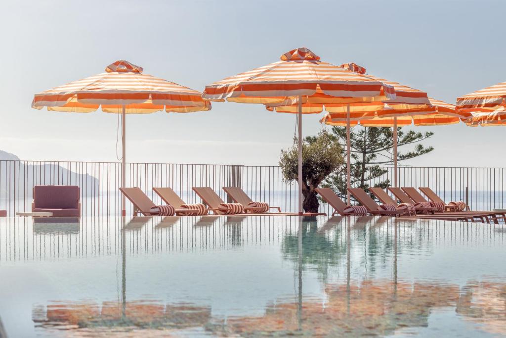 a pool with chairs and umbrellas next to a pool at NEXT - by Savoy Signature in Funchal