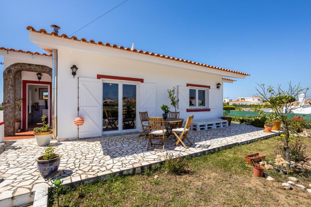 une petite maison blanche avec une table et des chaises dans l'établissement Villa Arrifana (Vale de Telha), à Aljezur