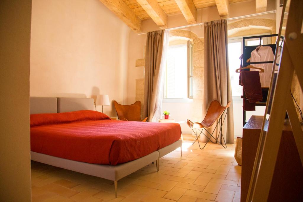 una camera con letto rosso e finestra di Locanda Carra Manna a Sassari